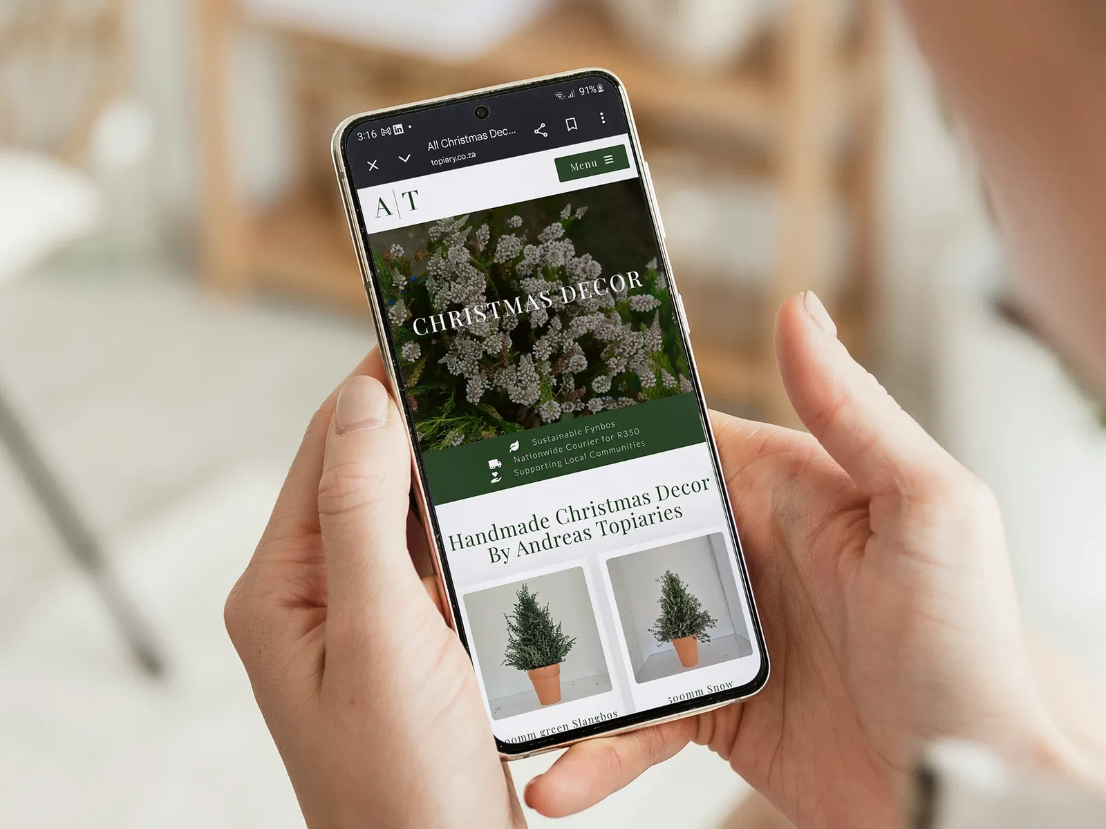 Andrea's Topiaries on a phone held in two hands: the Christmas decor, handmade trees in terracotta pots