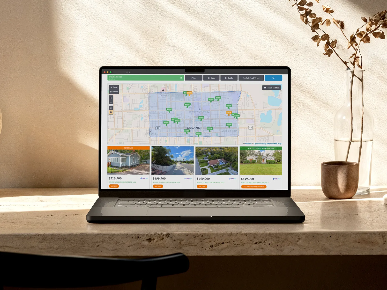 Greene Realty's listings on a laptop: a map of DeLand with the homes for sale beneath it