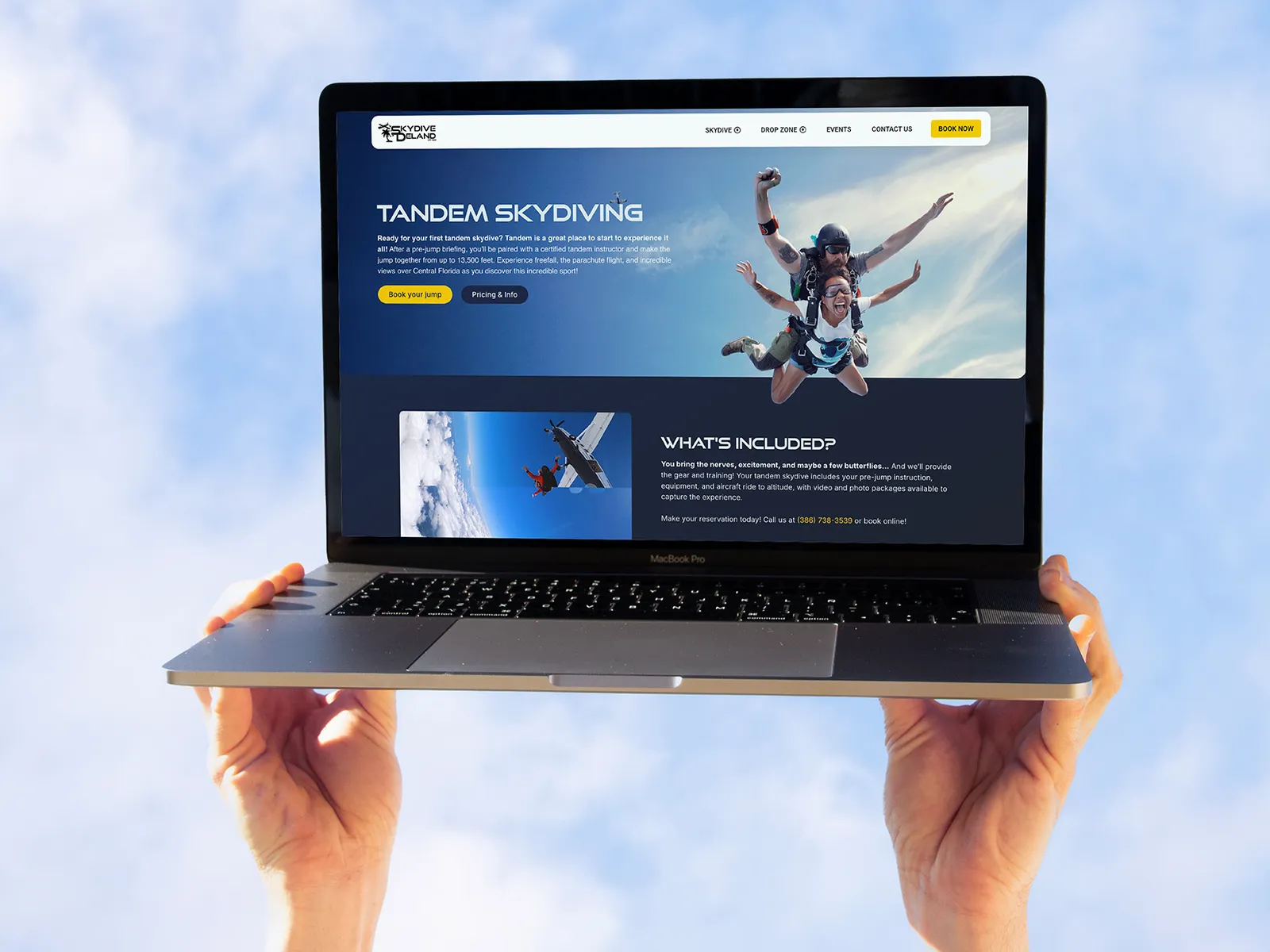 Skydive DeLand's Tandem Skydiving page on a laptop held up to the sky